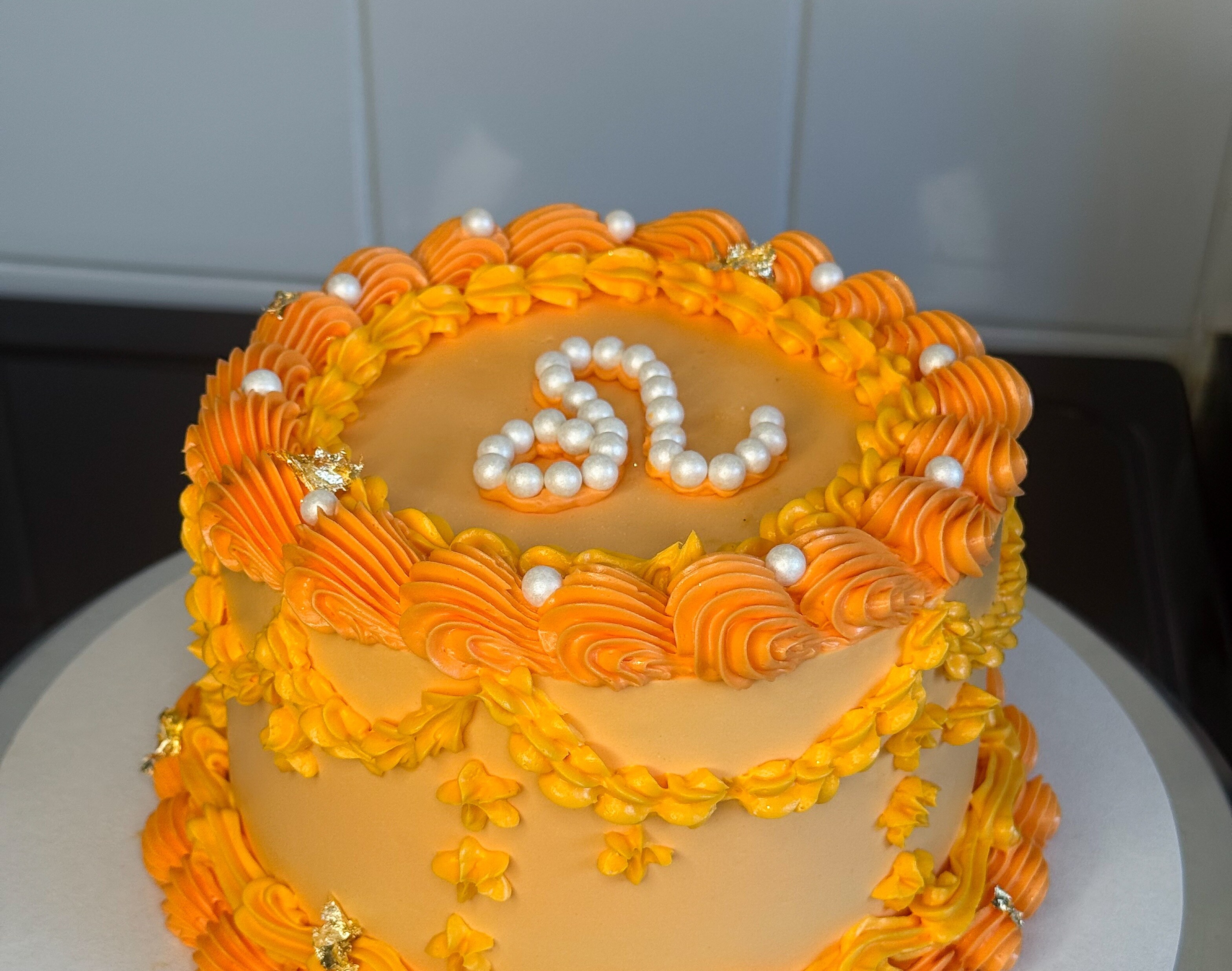 Orange buttercream celebration cake with a pearl number topper